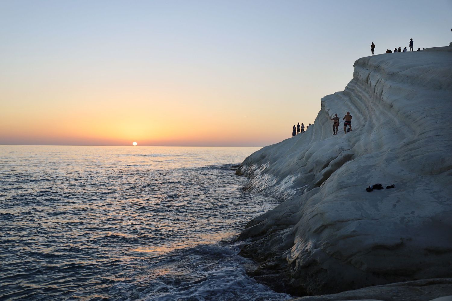 White chalk cliffs against sunset ocean view with dramatic coastal silhouettes.