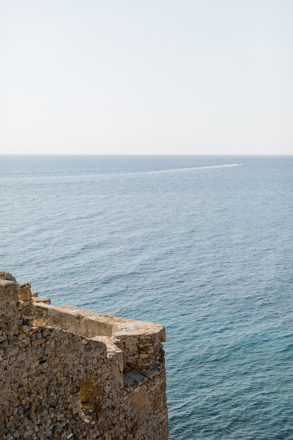 Dramatic coastal view of blue Mediterranean waters from an ancient stone fortress wall.