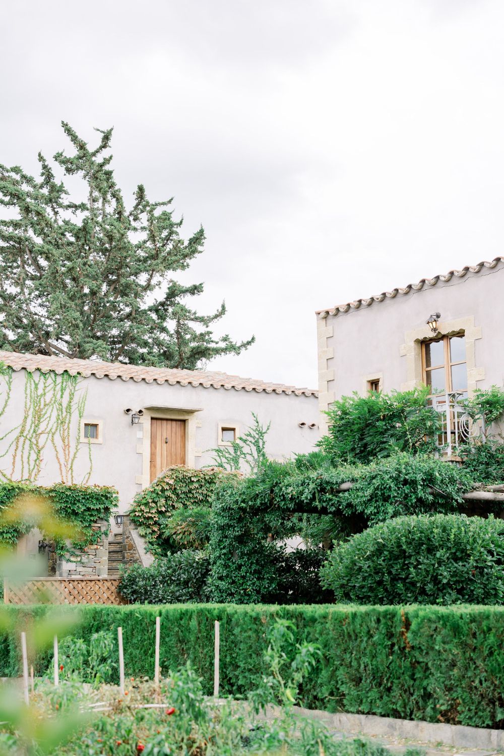 Mediterranean style white stucco building with terracotta roof and lush garden landscaping.