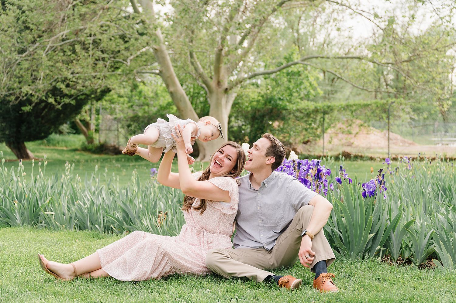 A playful family moment on a spring day with purple iris flowers blooming in a lush garden setting.