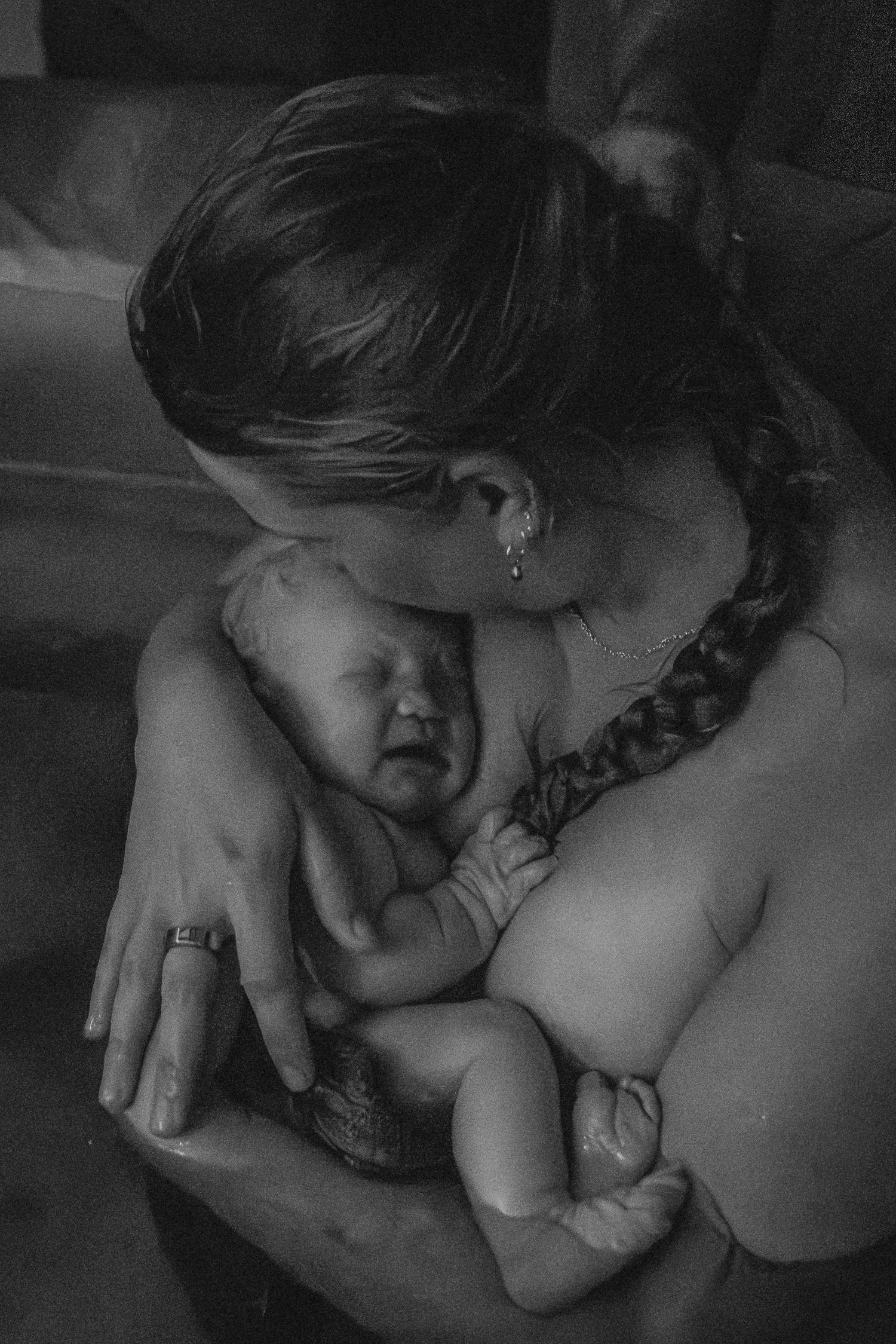 Intimate black and white portrait showing tender moment between caregiver and infant.