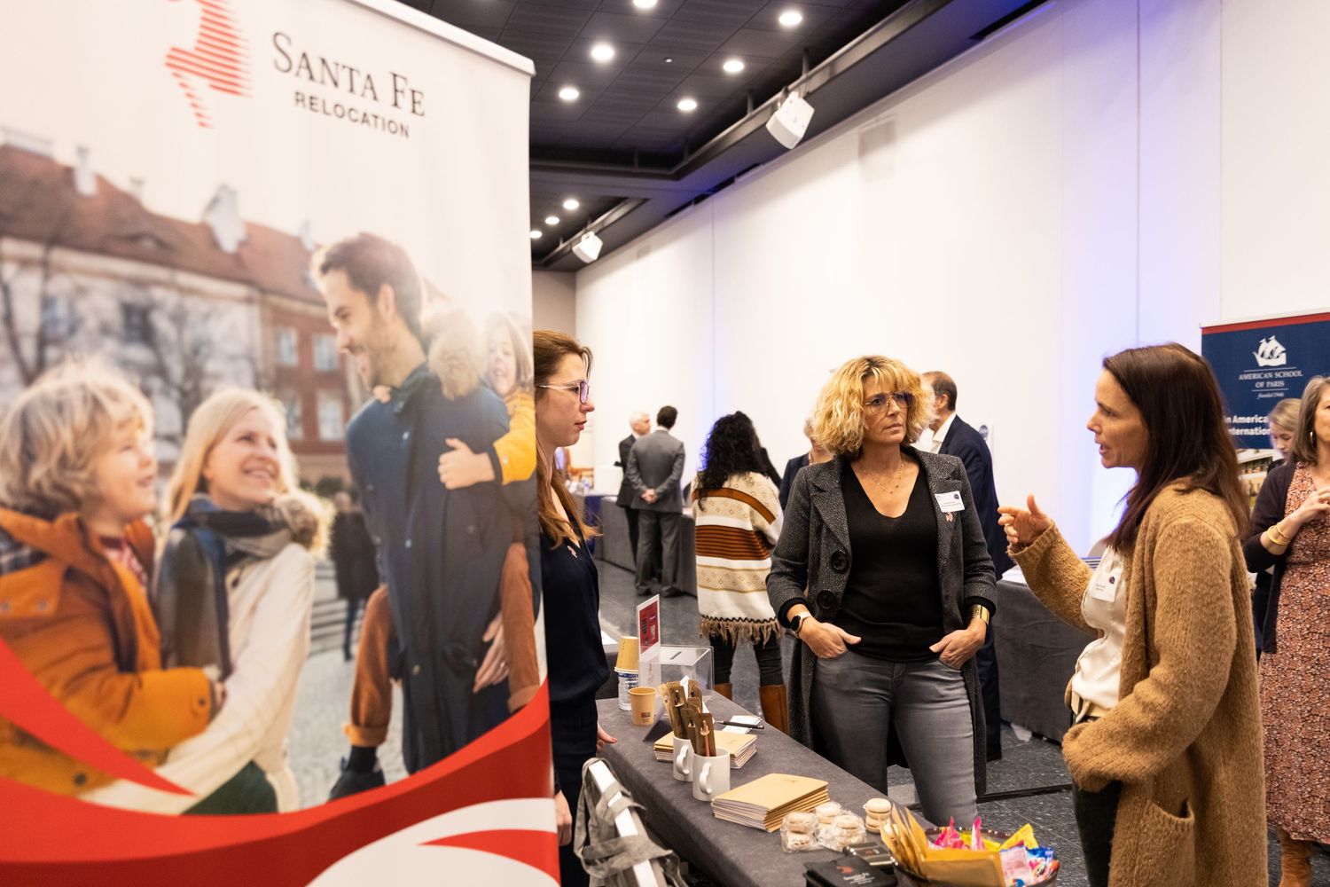 Trade show booth with Santa Fe banner showing people networking and discussing products.