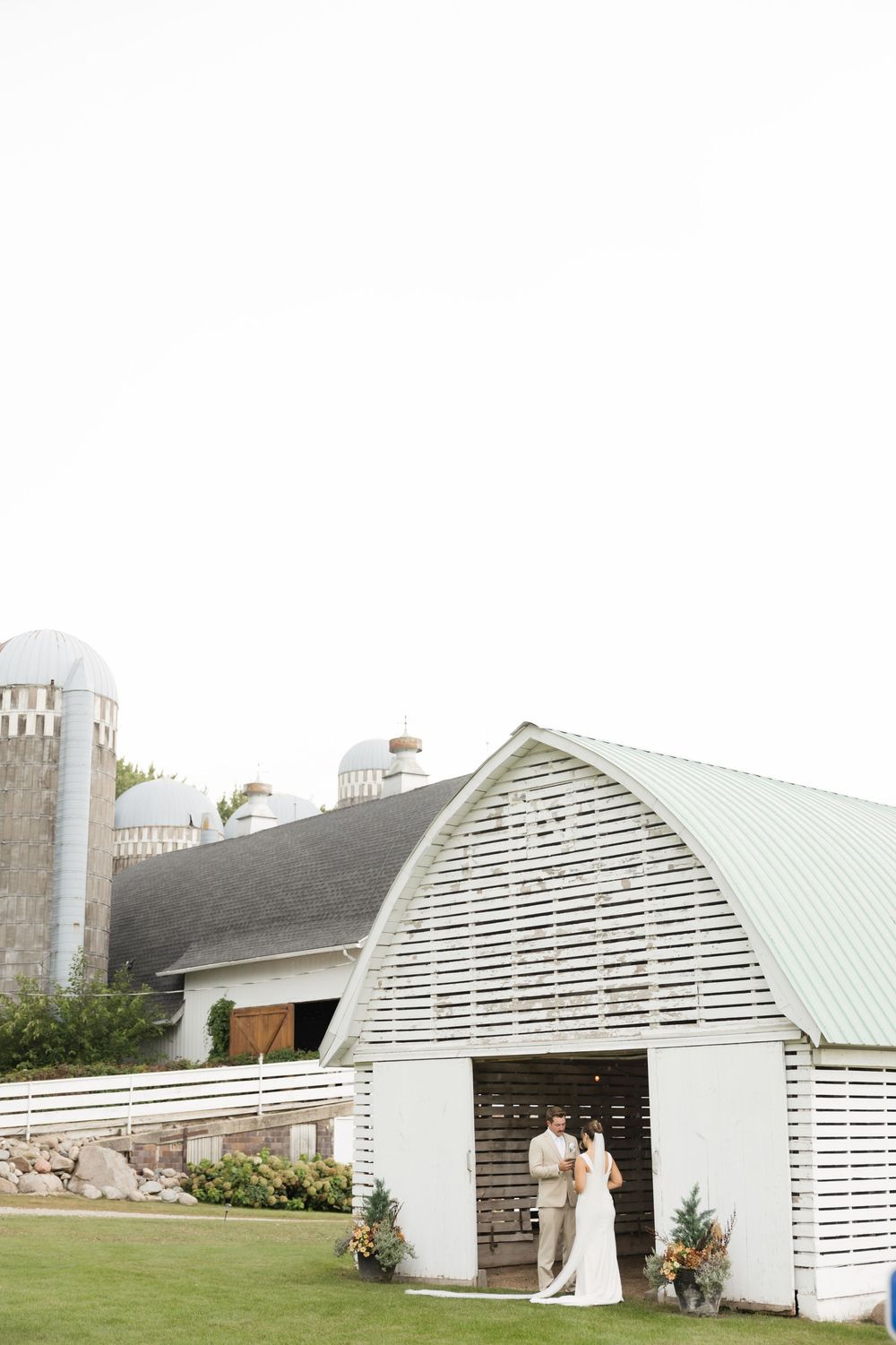 White wedding venue with arched roof and elegant architecture set against a scenic countryside backdrop.
