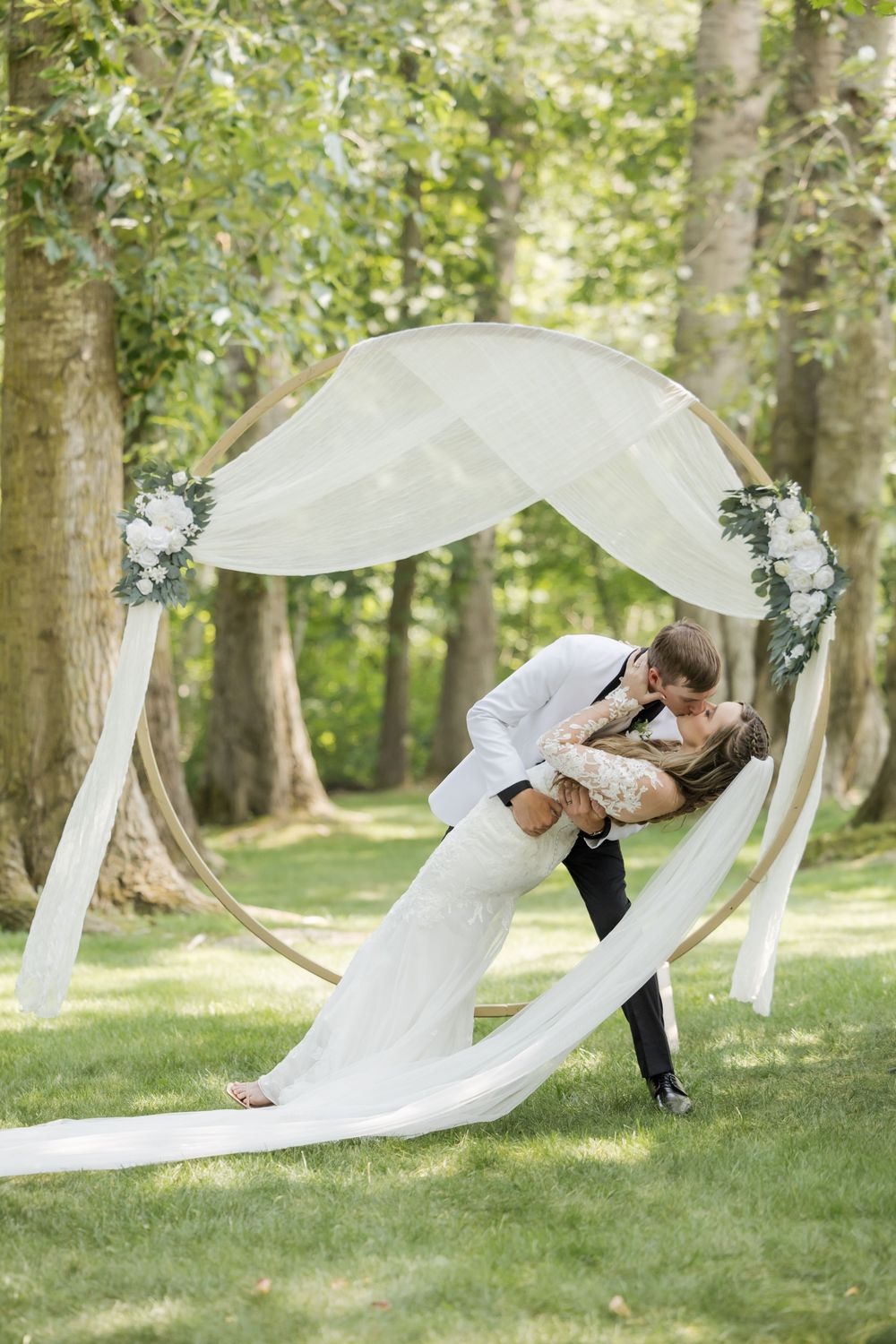 A flowing white veil billows dramatically in the wind during an outdoor wedding photoshoot.