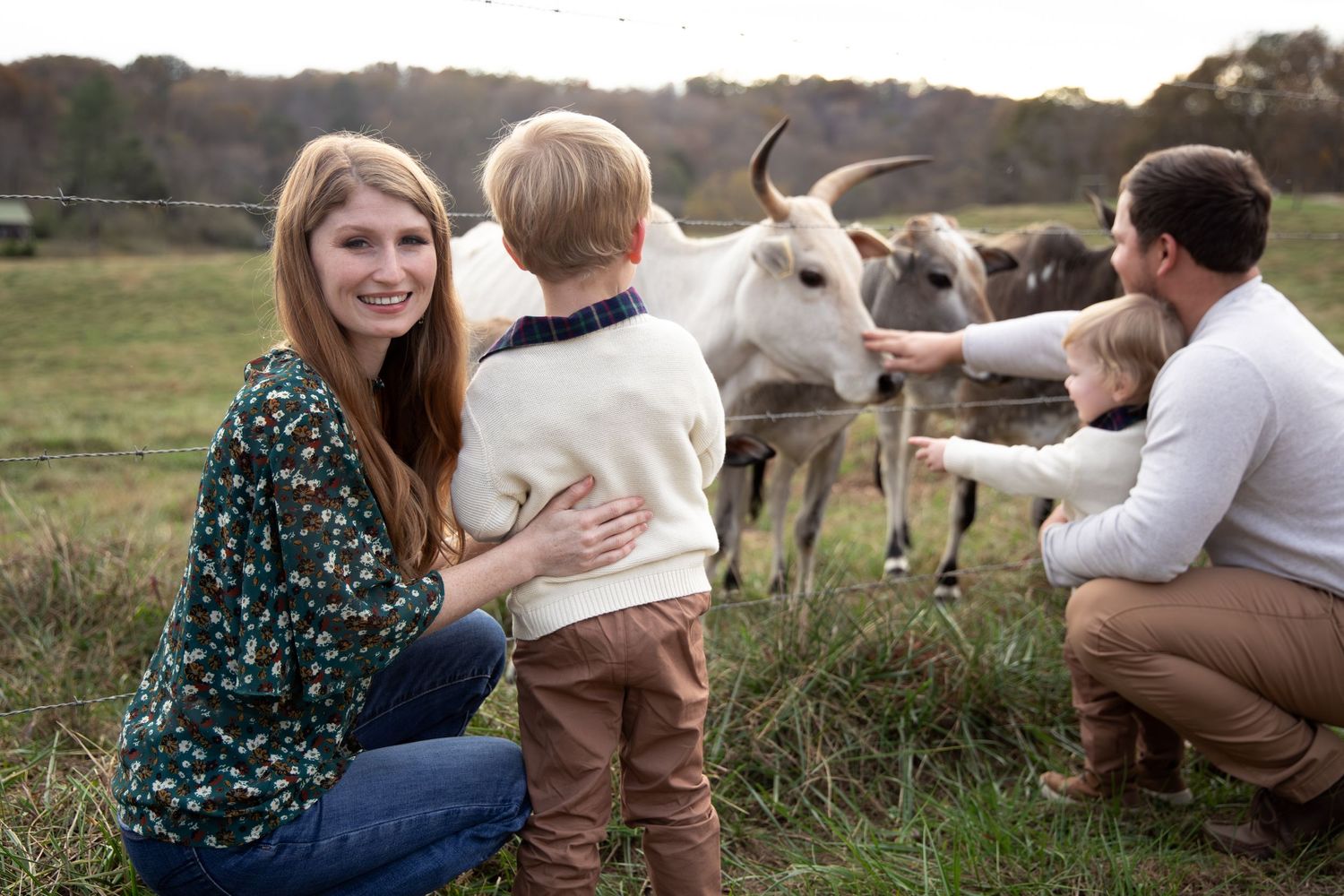Family enjoying time together outdoors with farm animals visible in the background.