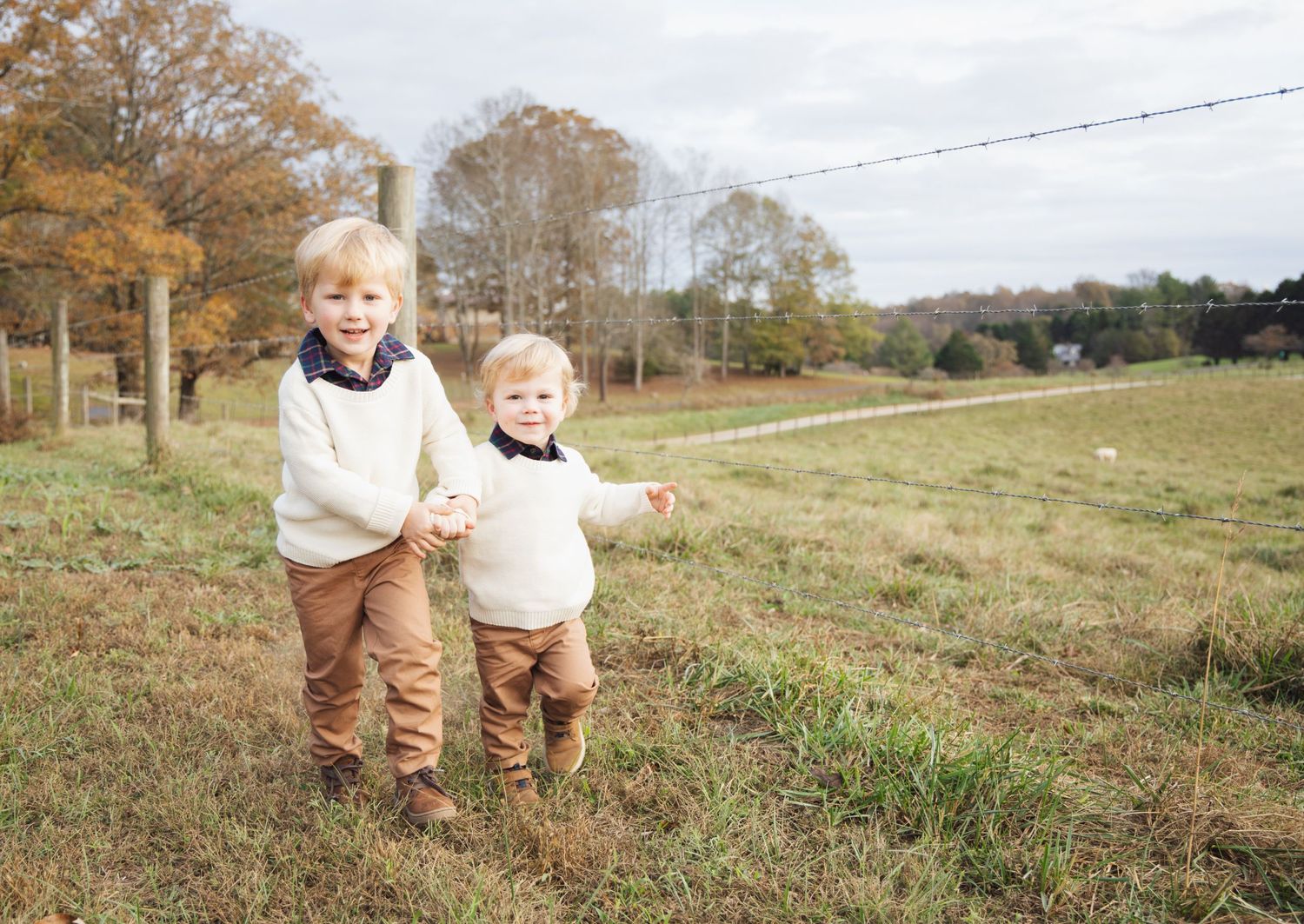 A joyful moment captured in a sunny autumn field with rolling hills.