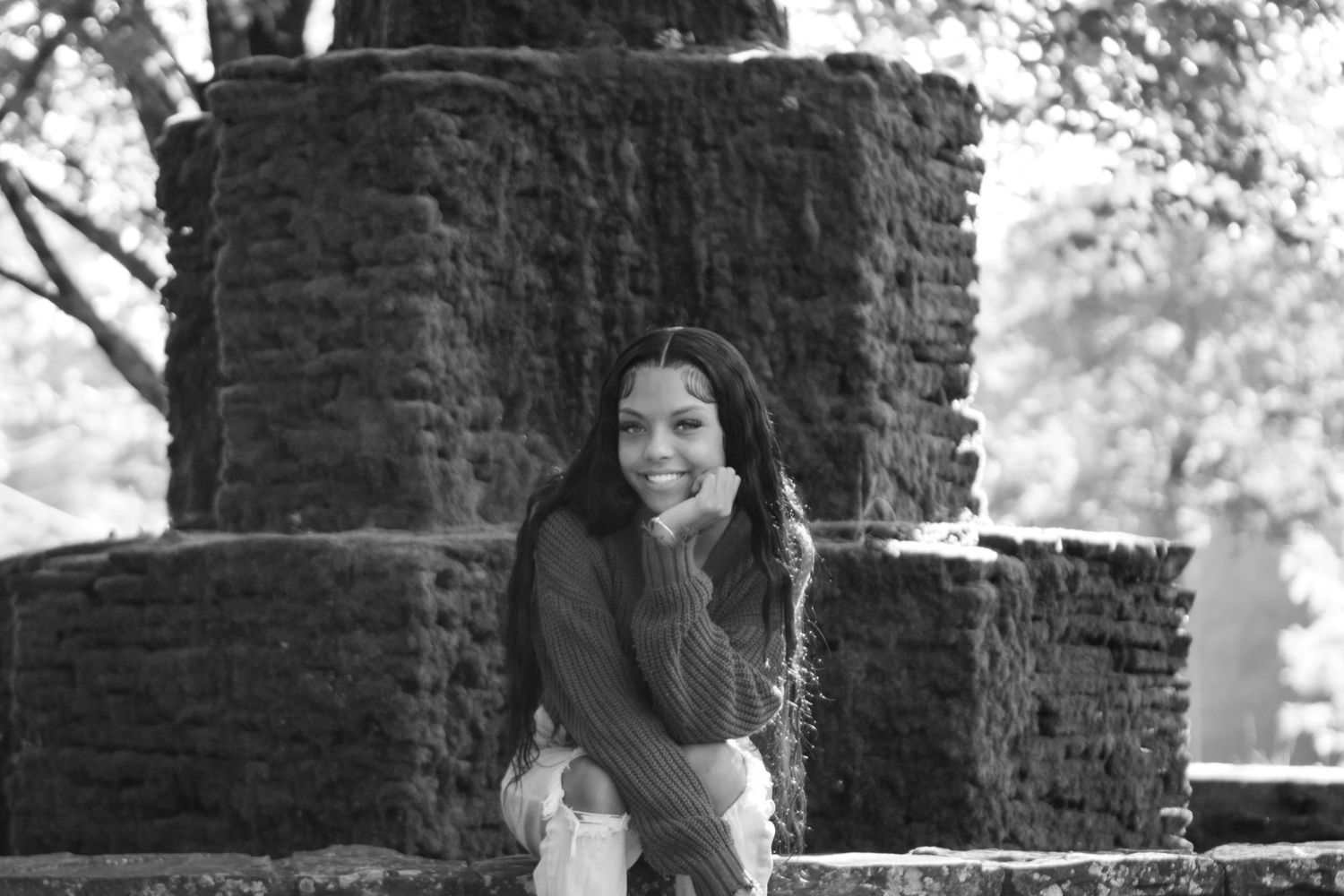Person standing between stone pillars in outdoor setting.