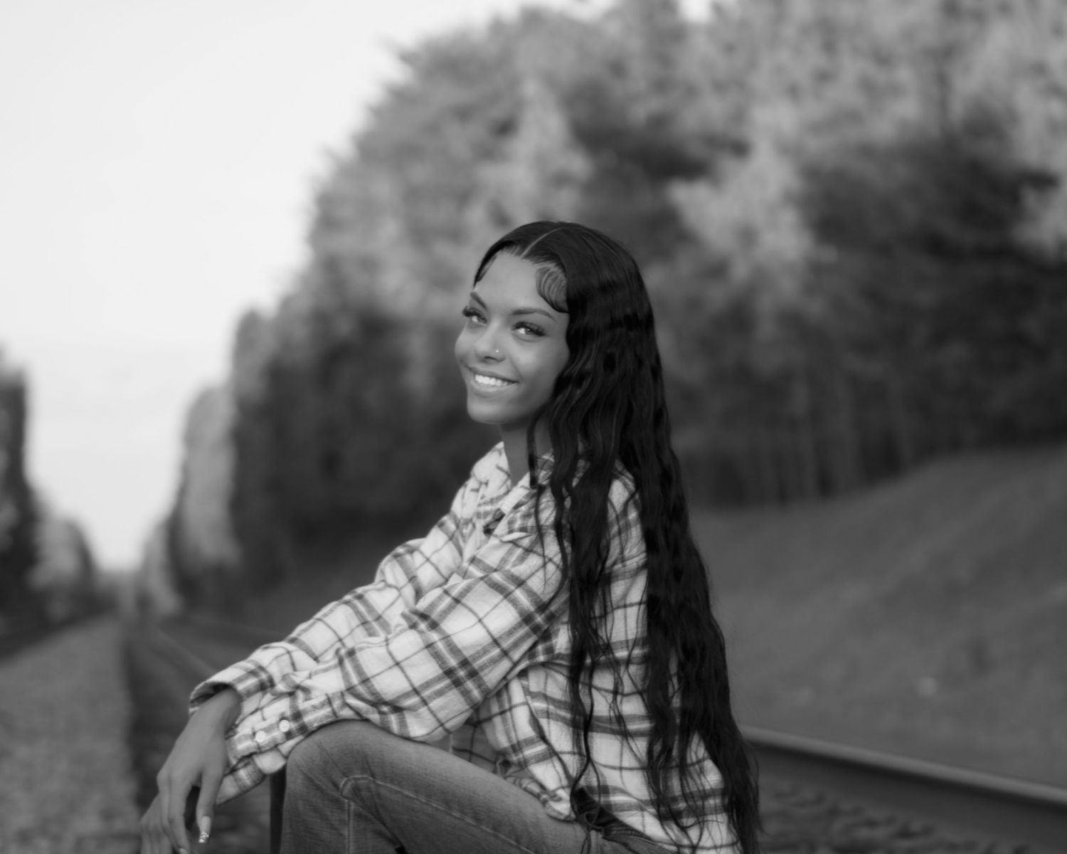 Black and white portrait session along railroad tracks featuring a plaid shirt and casual style.