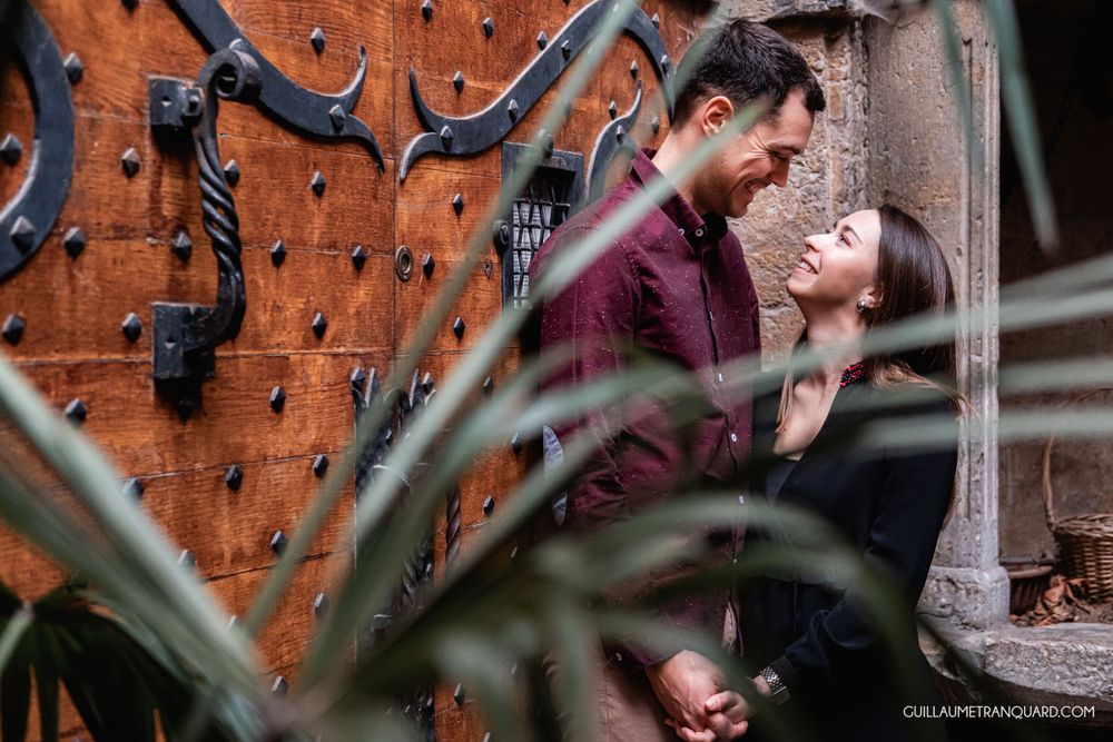 Couple embracing against rustic orange brick wall with climbing plants.