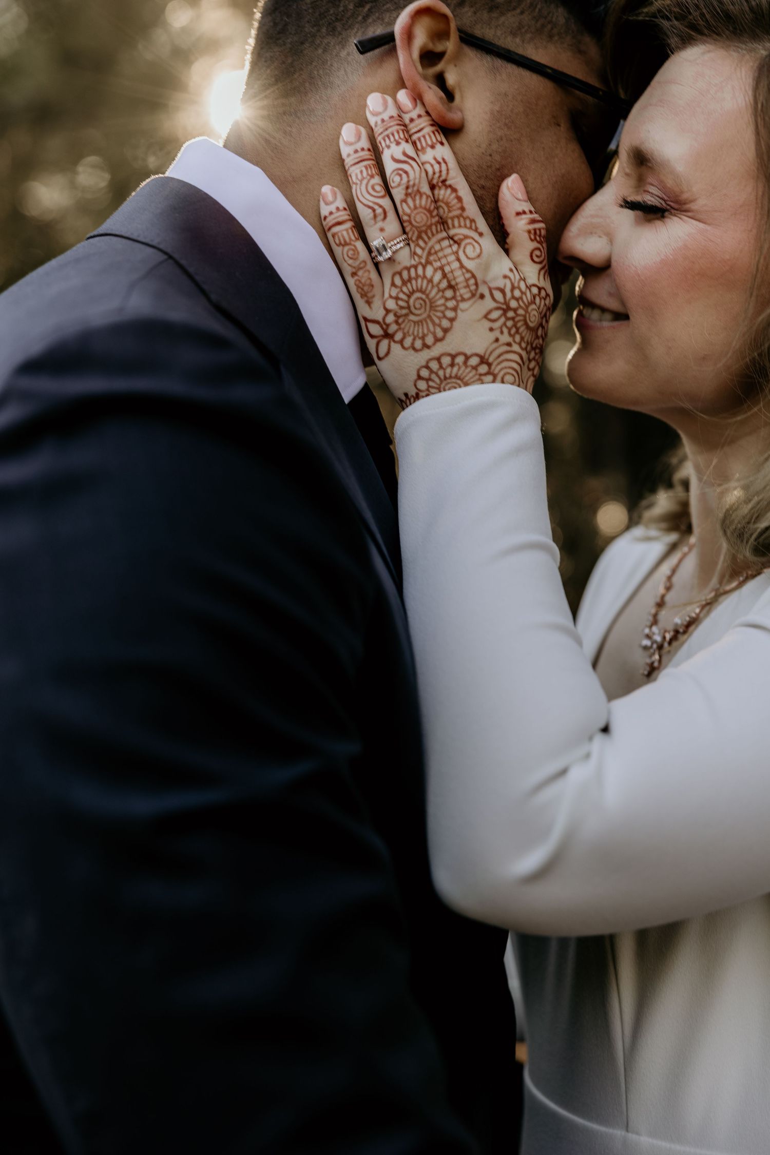 Close-up sequence of intimate wedding couple moment showing hands with henna and white dress sleeve details.