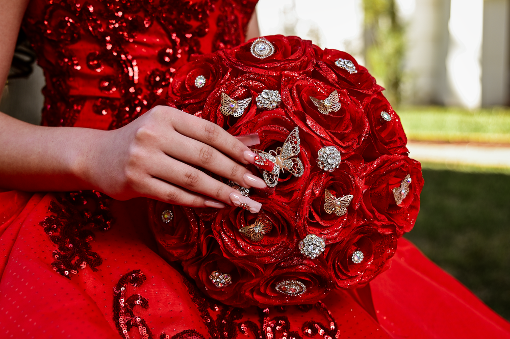 Close-up of a red crystal-embellished bouquet with sparkling details against a red dress.