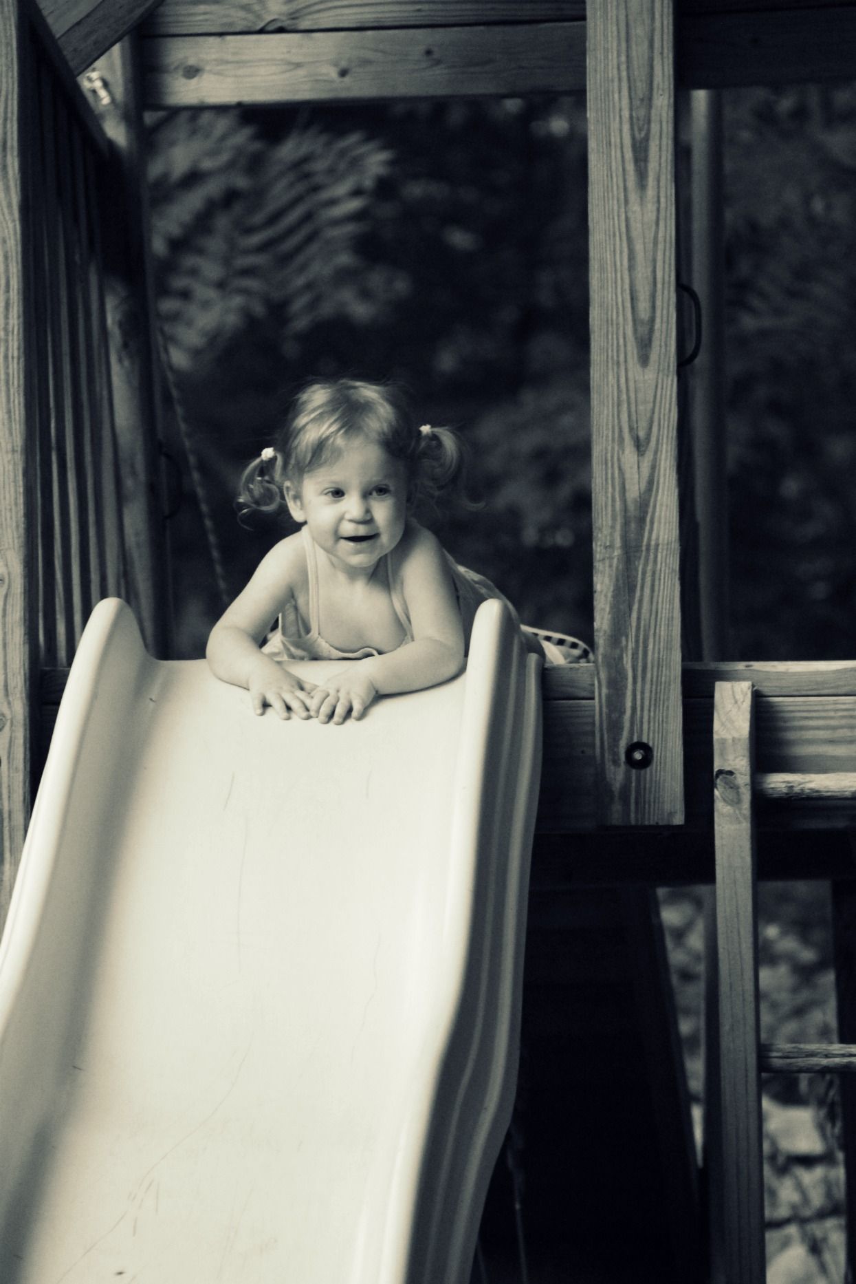 a little girl poses at the top of a slide