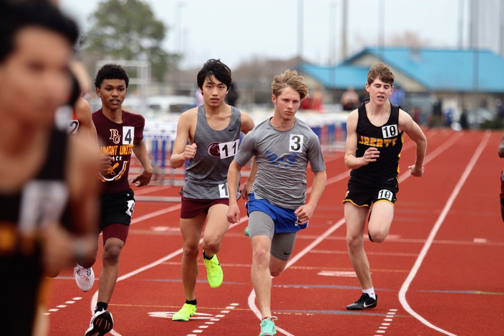 Track athletes in starting position for a sprint race on an outdoor track.
