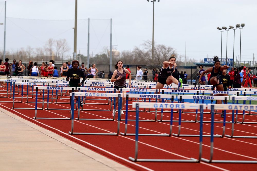 Multiple hurdle lanes set up on a red running track for a competitive race event.