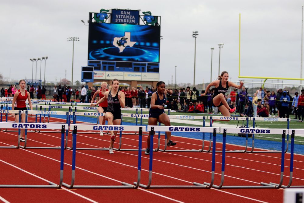 Wide view of a track and field stadium with hurdles set up for competition.