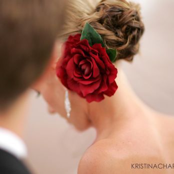 Detailed view of a red rose hair accessory nestled in an elegant braided updo.