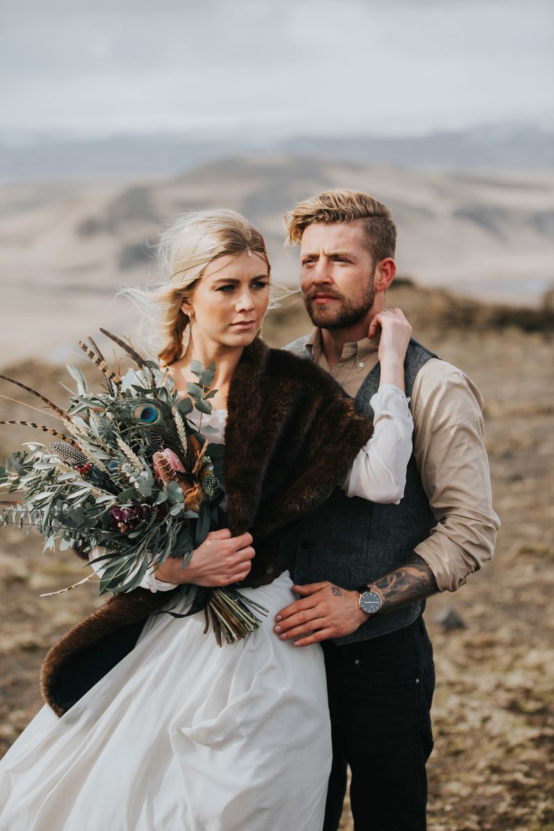 A winter wedding portrait featuring a rustic bouquet and elegant white dress against mountain backdrop.