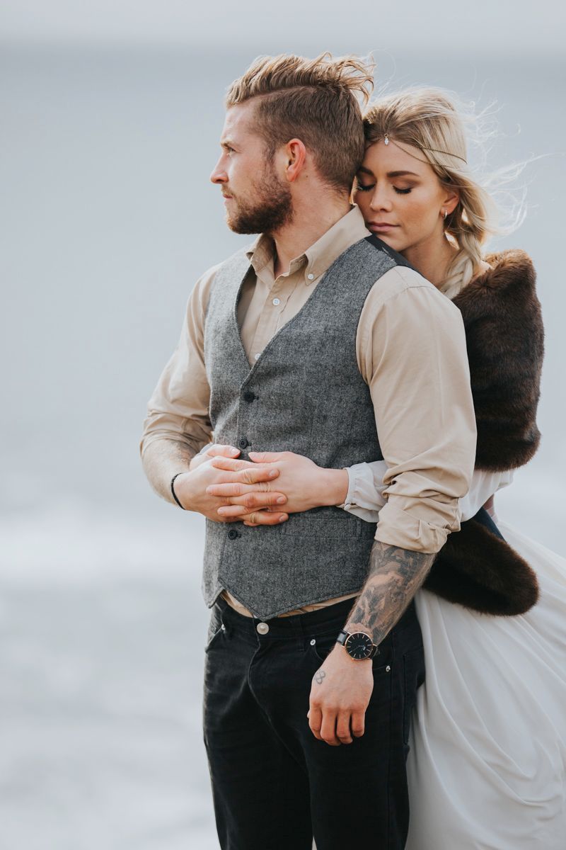 Intimate coastal wedding portrait capturing tender moment against misty ocean backdrop.