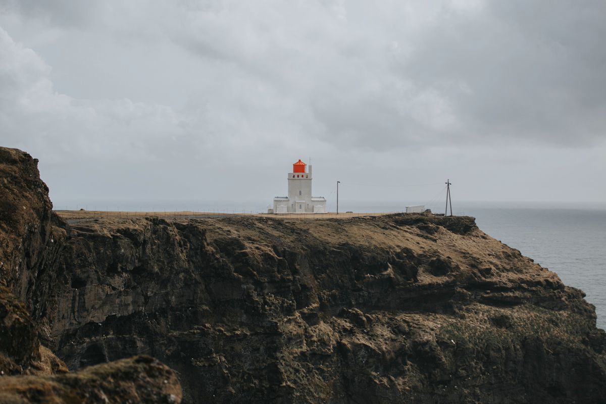 A lighthouse perched atop dramatic coastal cliffs under moody gray skies.