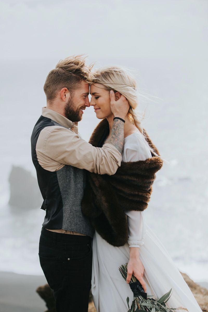 Emotional wedding moment captured between couple on coastal overlook.