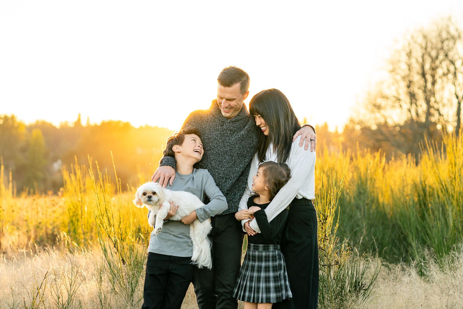 Family smiling with their dog at Marymoor at sunset.
