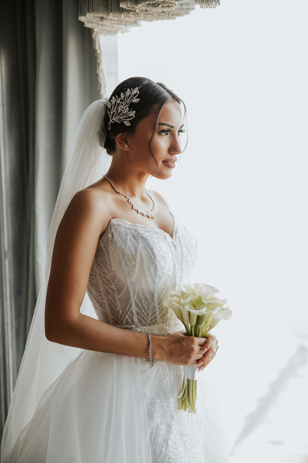 Side profile of bride in detailed lace gown with ornate hair accessory.