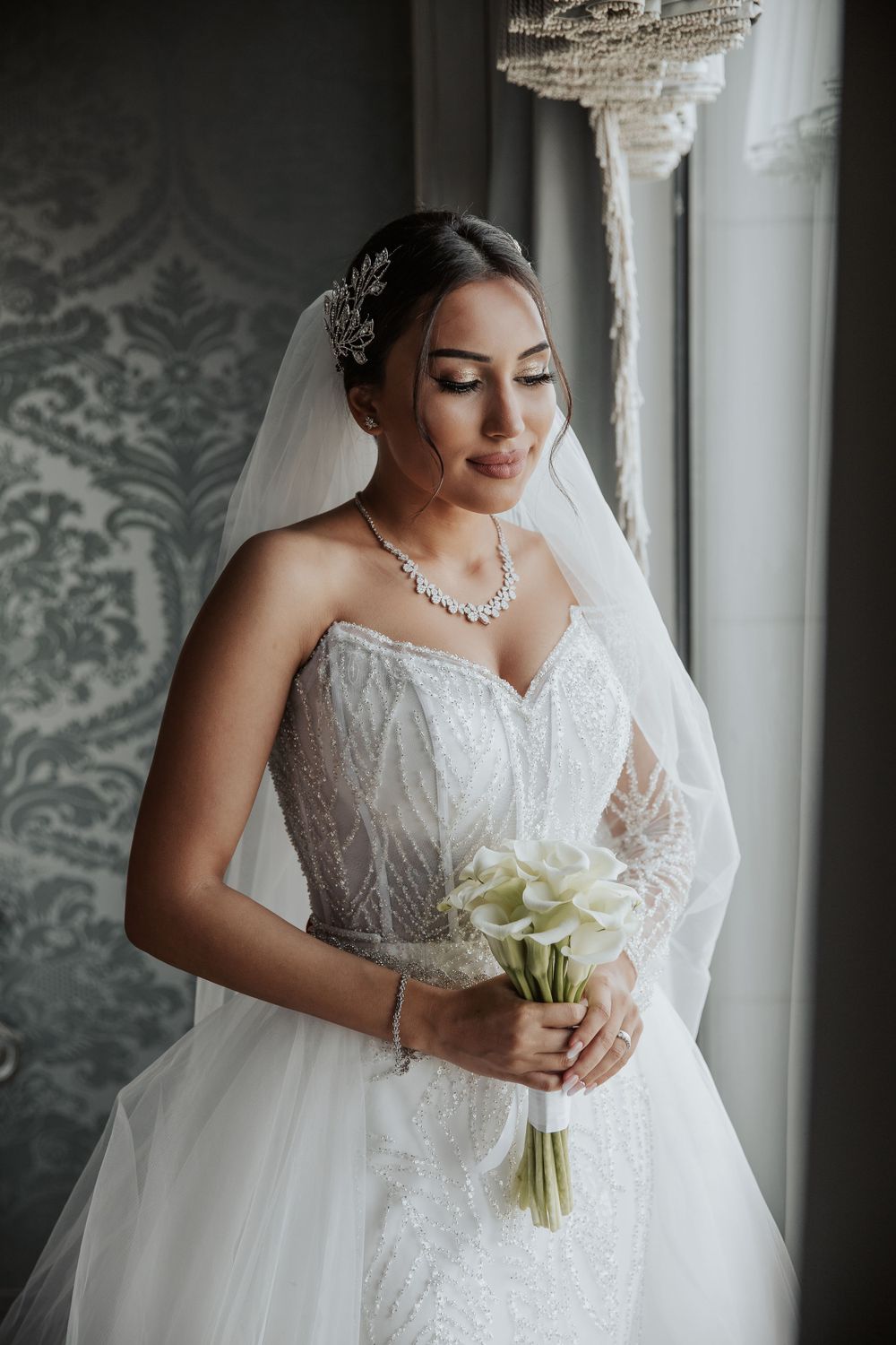 Classic bridal portrait featuring strapless lace gown and white calla lily bouquet.