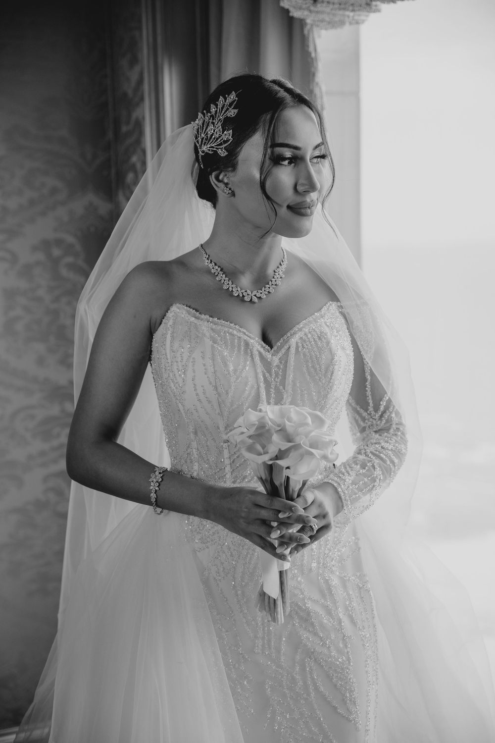 Dramatic black and white bridal portrait with ornate hair accessory and necklace.