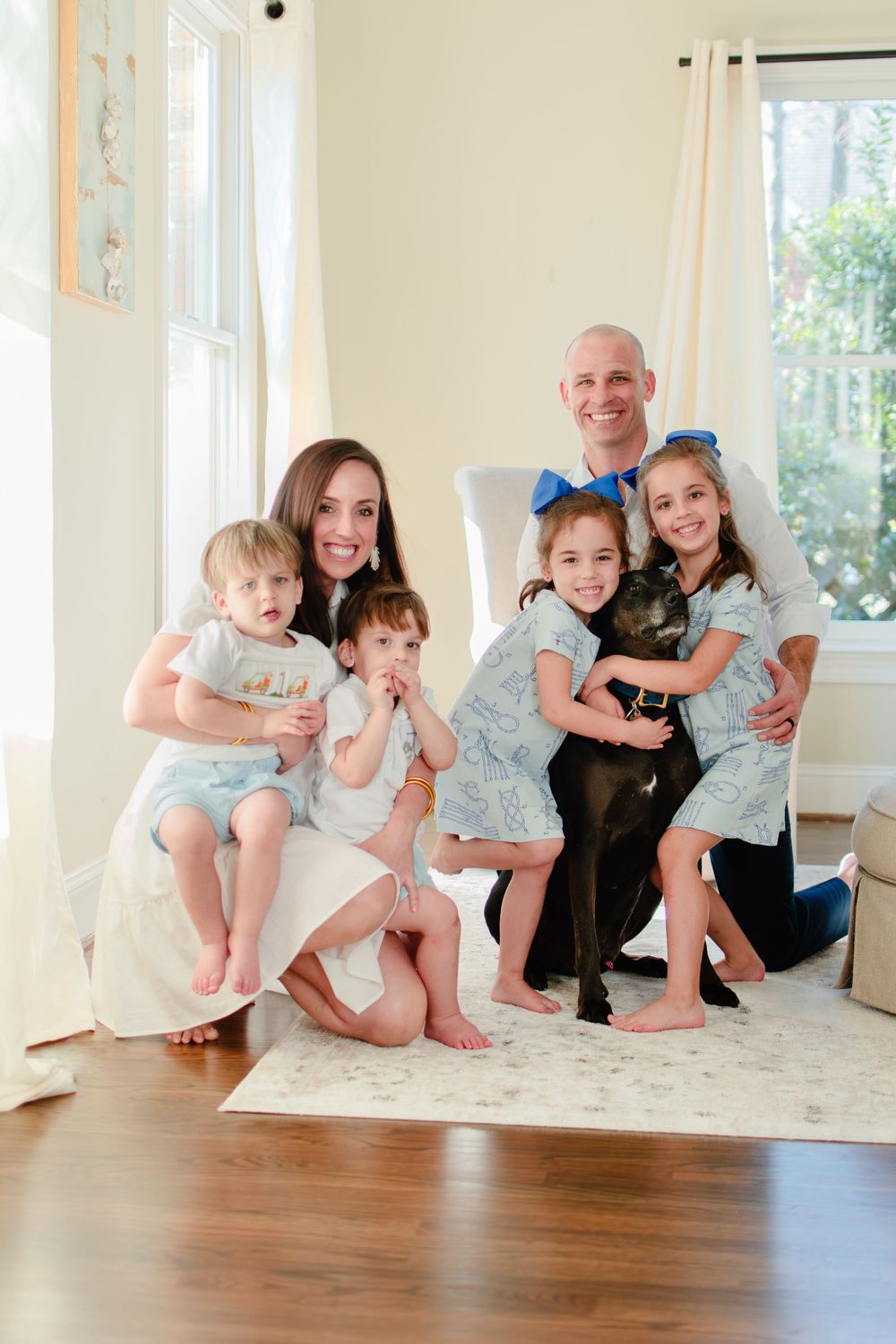 The family's dog joins the photo as the six of them smile in their den.
