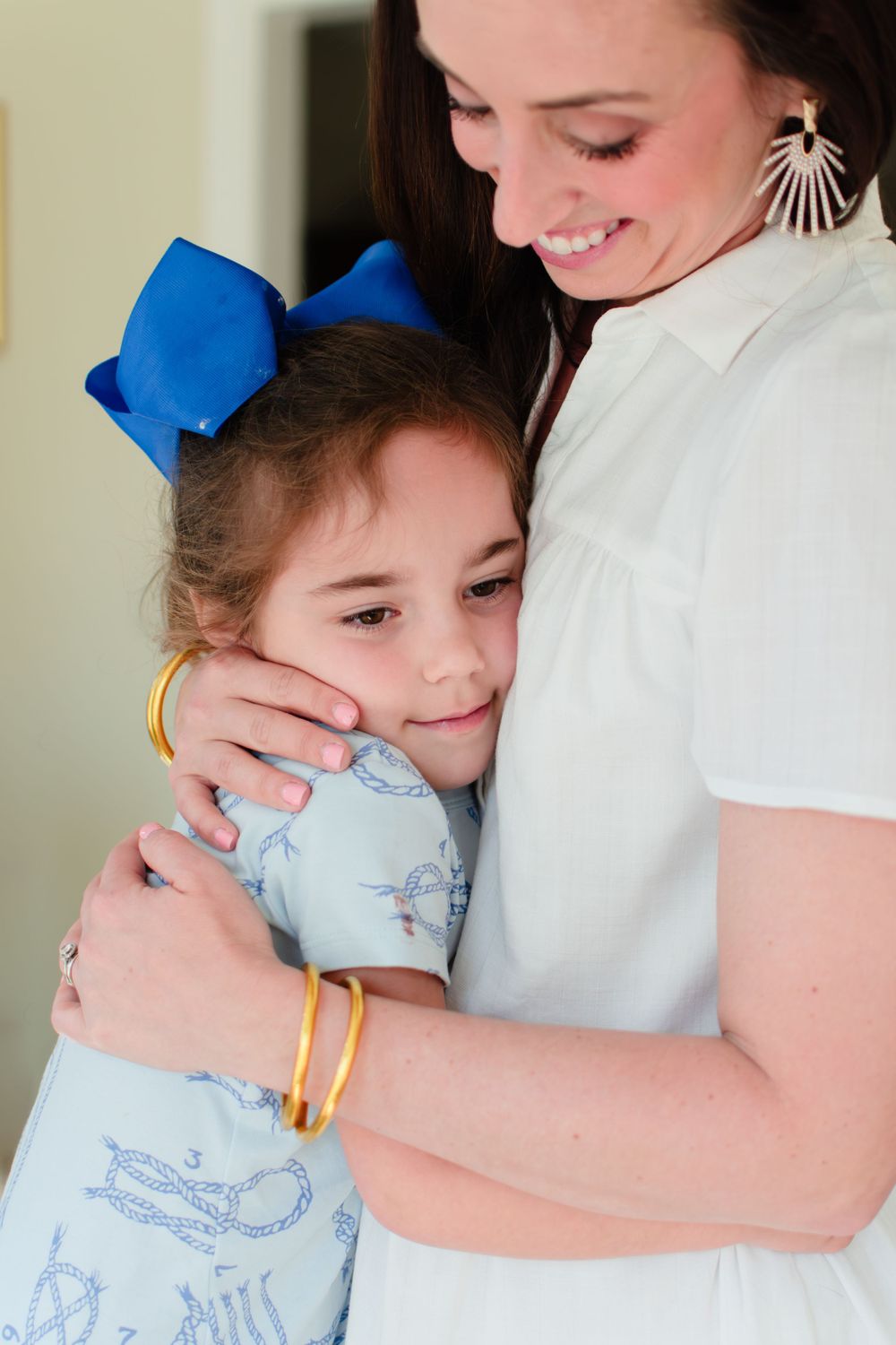 Mom hugs her daughter as the girl tenderly relishes in this embrace.