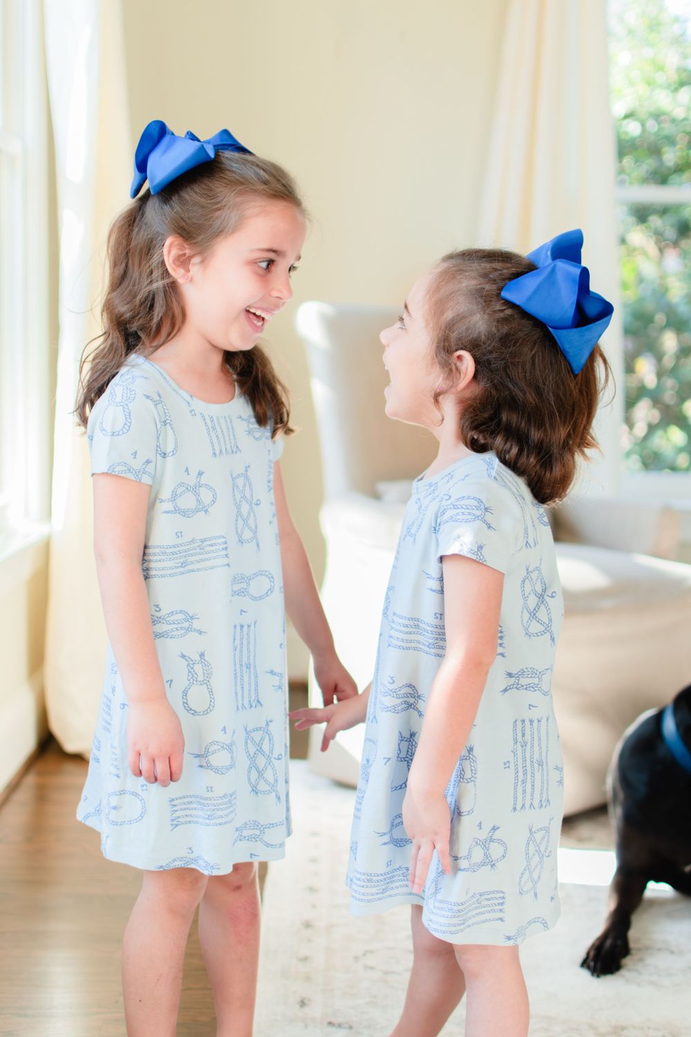 Two sisters hold hands and laugh as they stare in each other's eyes.