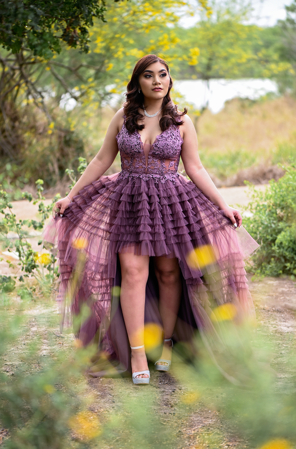 High-low purple tulle dress photographed on nature path with yellow wildflowers.