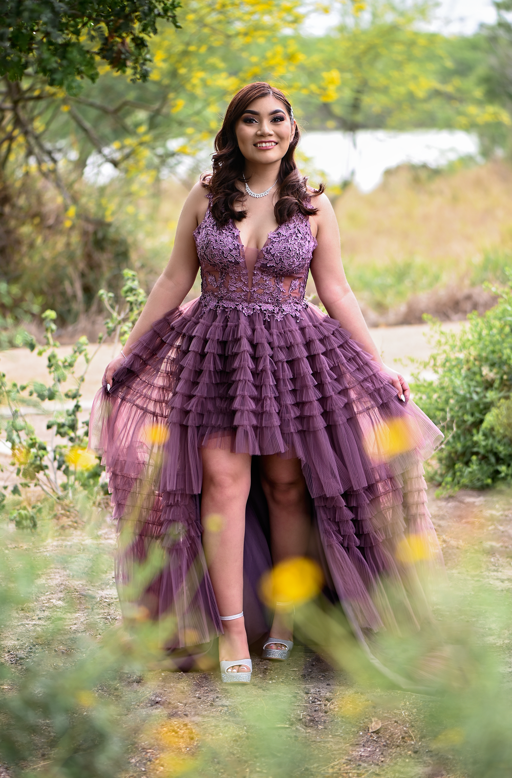 Playful portrait in purple high-low dress with tiered tulle skirt outdoors.