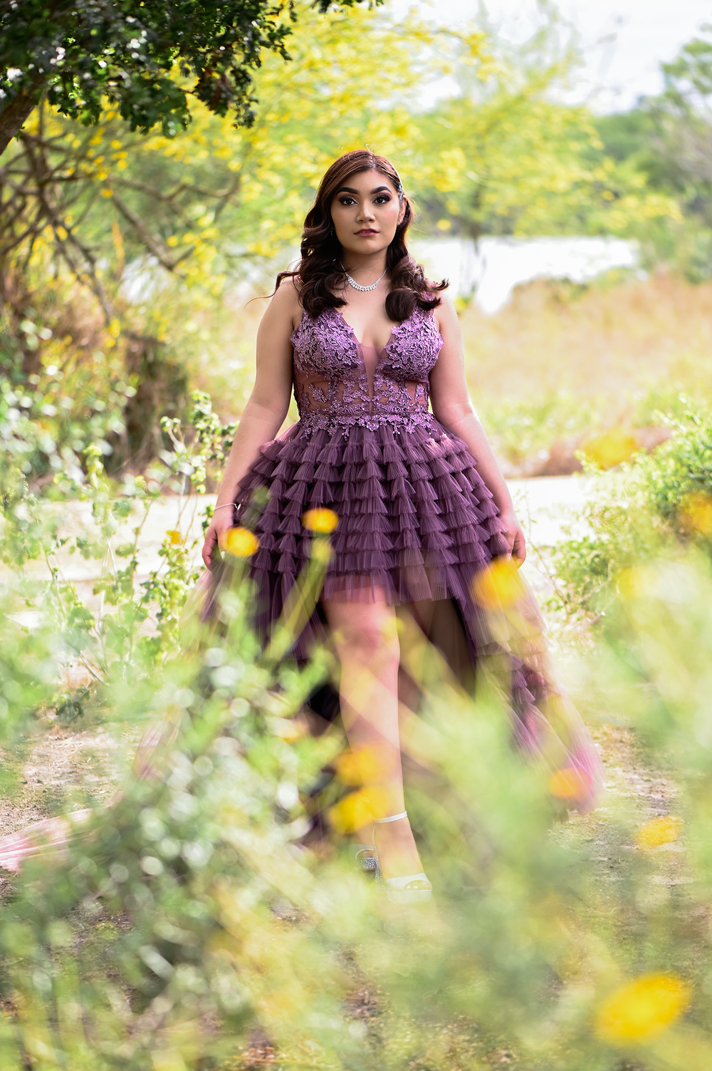 Elegant mauve tulle gown with lace bodice photographed in garden setting with yellow wildflowers.