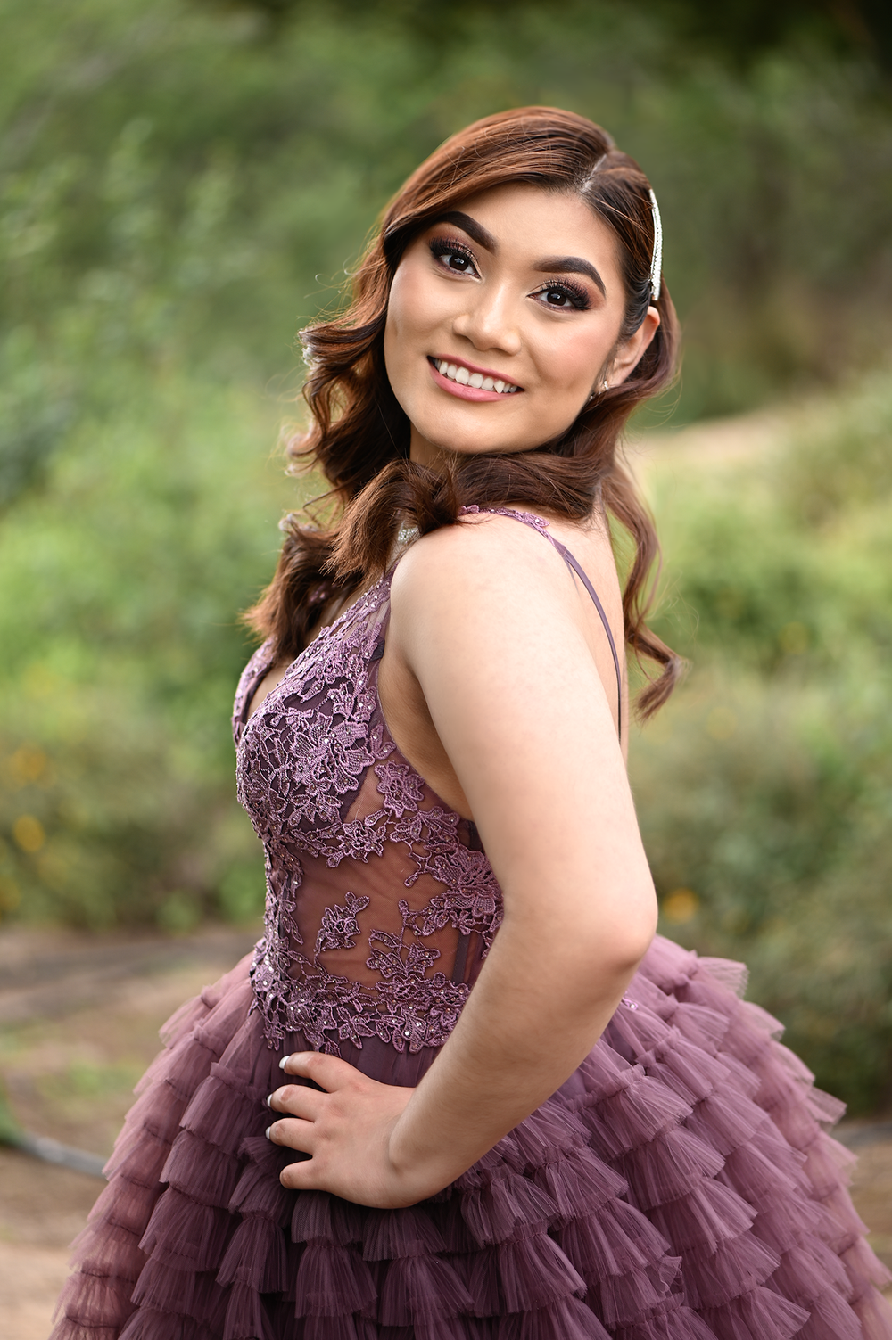 Close-up shot of purple lace and tulle formal dress with detailed bodice in garden setting.