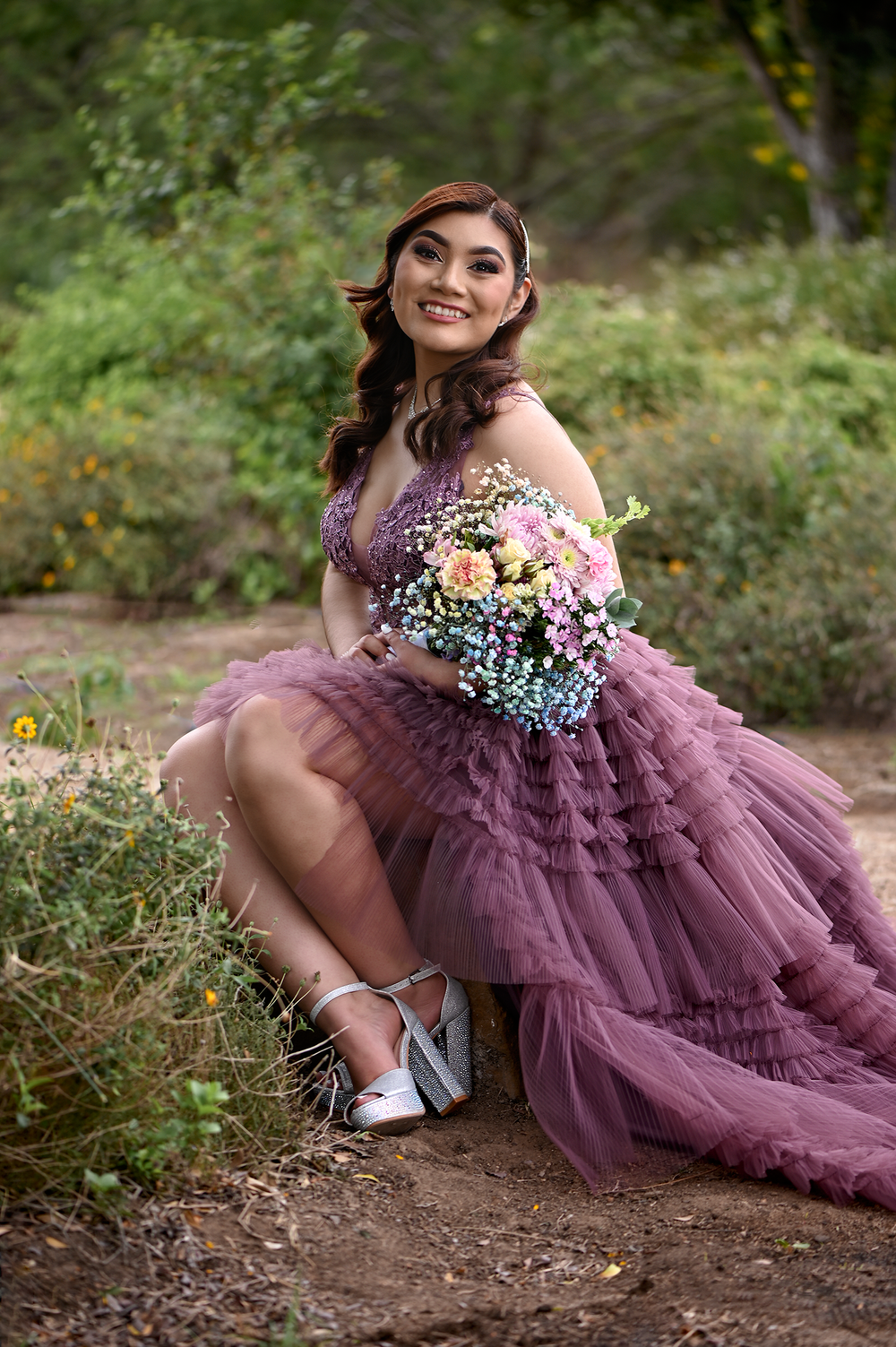 Purple high-low gown with mixed floral bouquet photographed in outdoor garden setting.