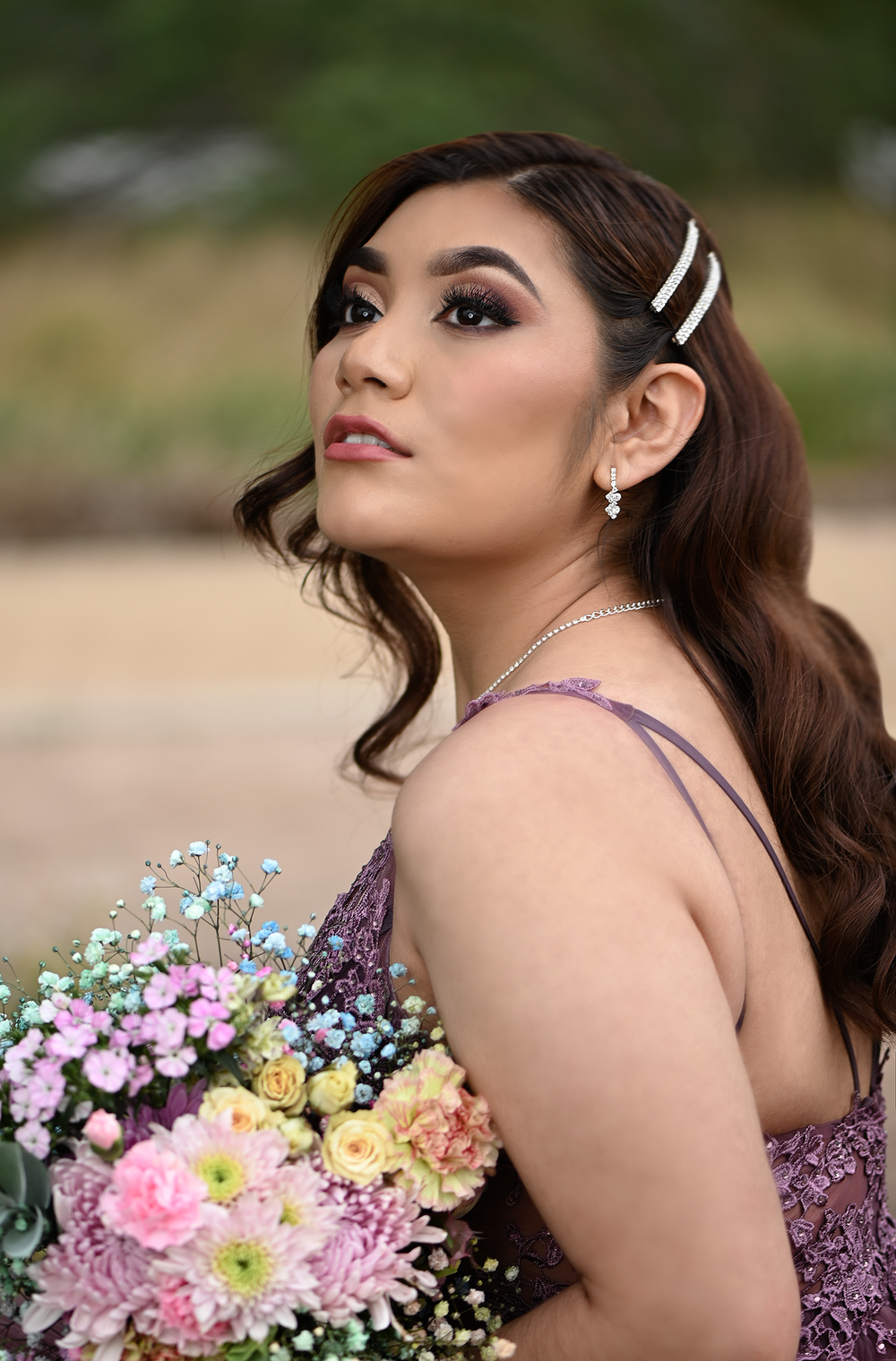 Side profile shot of formal dress with crystal hair accessories and pastel floral bouquet.