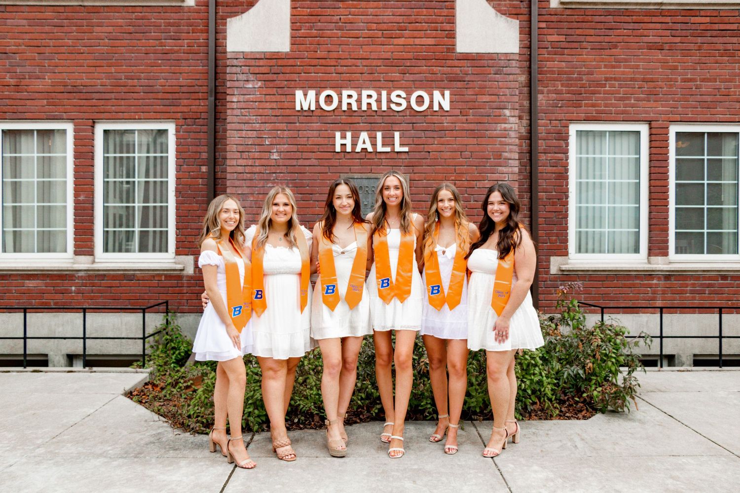 A group of grads standing in front of a dorm building