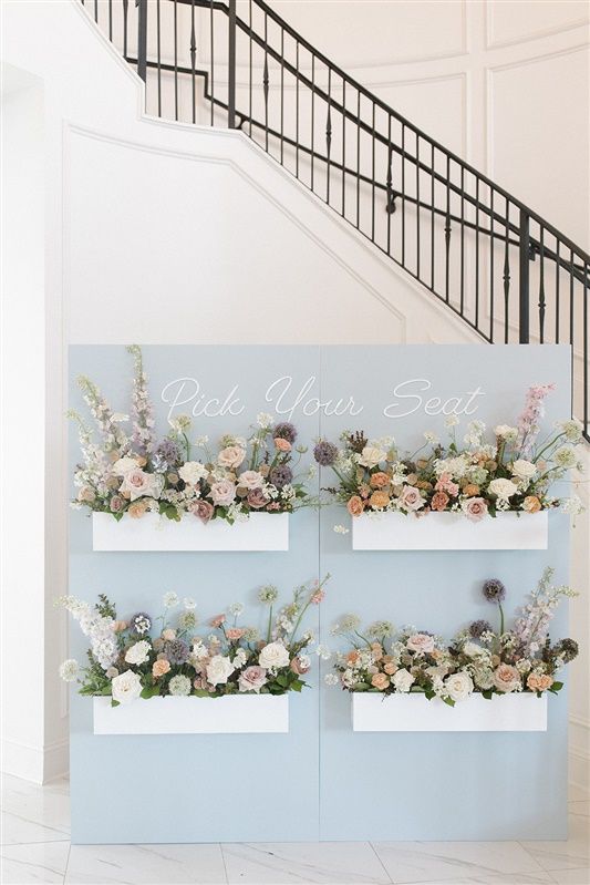Elegant floral display with four white boxes mounted on a light blue backdrop featuring blush roses and delicate blooms.