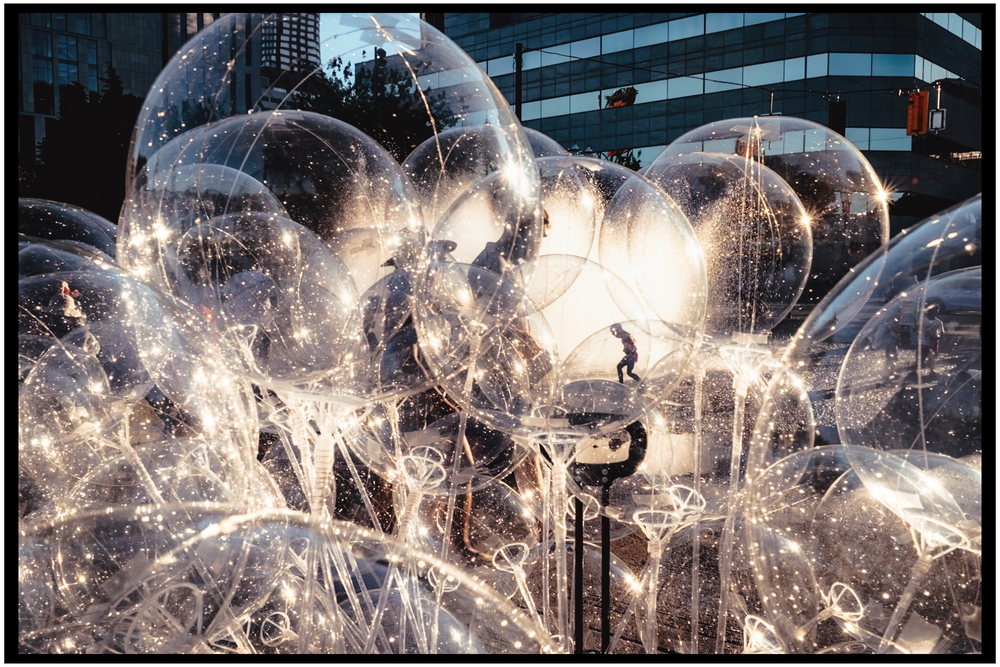 Illuminated frozen soap bubbles creating ethereal light patterns against dark background. Portland street photography