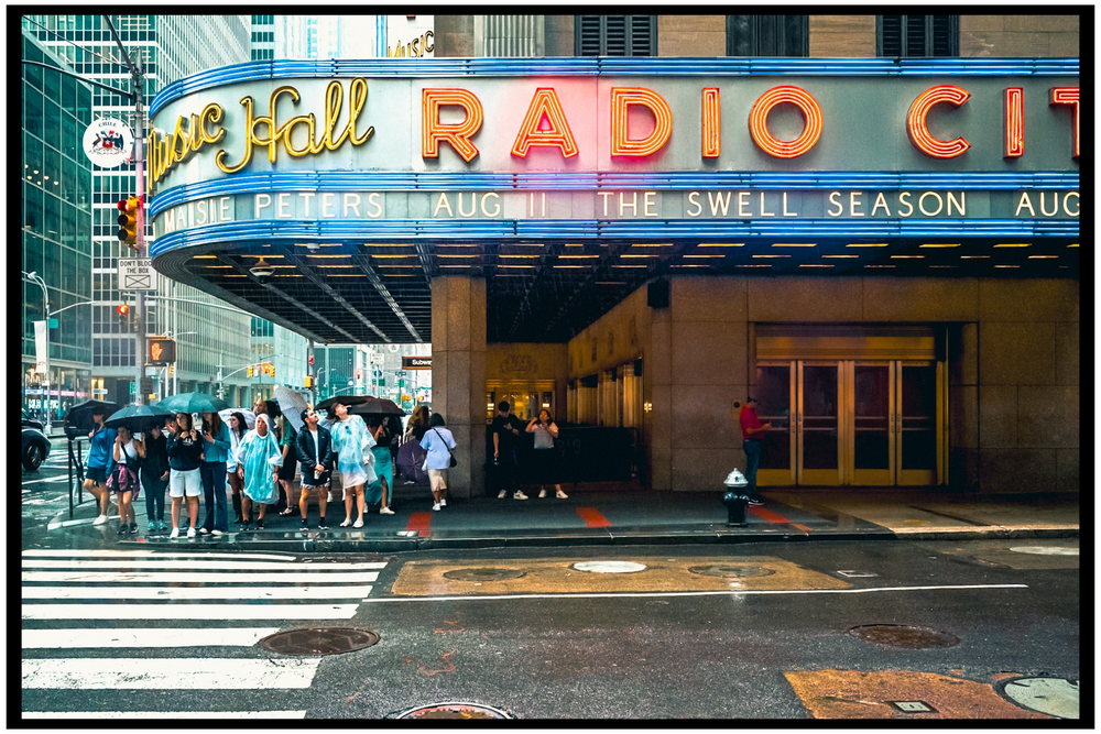 People queue outside the iconic Radio City Music Hall marquee in New York City. NYC street photography