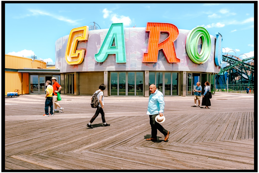Colorful vintage sign on Coney Island boardwalk with people walking beneath it. NYC street photography