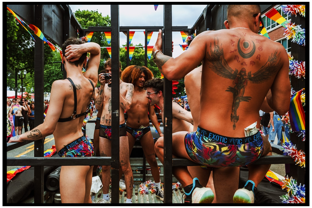 Muscular athletes working out on outdoor exercise equipment at a pride festival. Portland street photography