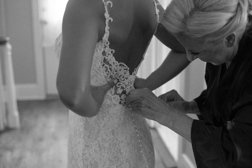 Close-up of wedding dress being buttoned up during bridal preparations.