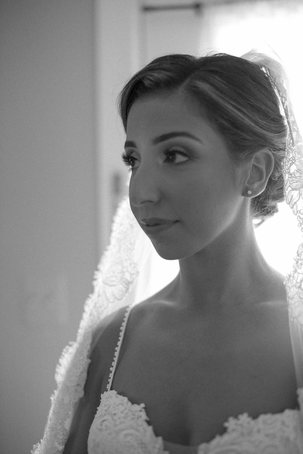 Classic black and white bridal portrait showing elegant updo hairstyle and lace dress details.