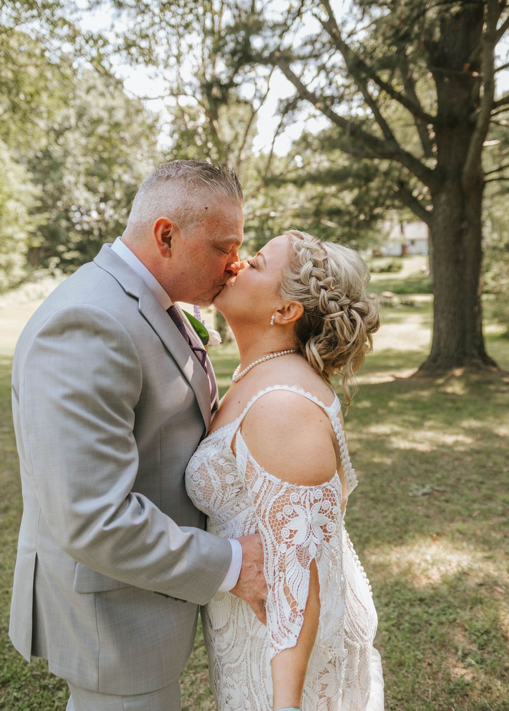A couple shares an intimate moment during their wedding photoshoot in a sunlit park.