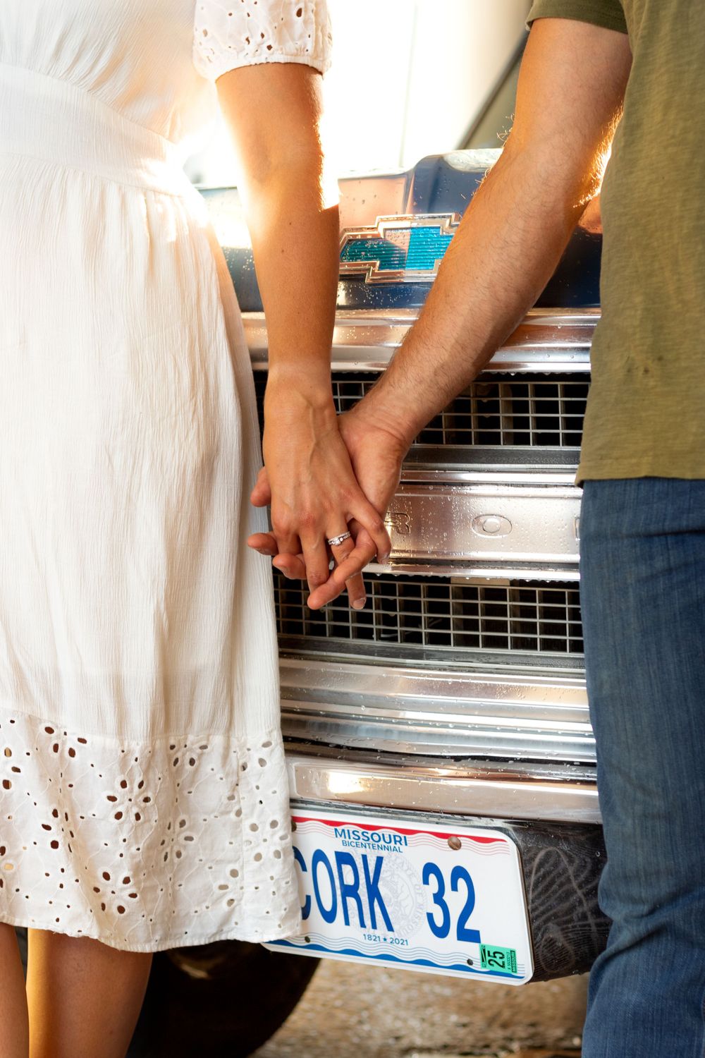 A couple holding hands in front of a vintage car with a York 32 license plate.