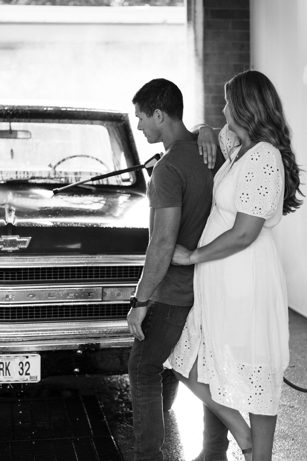 Couple standing beside their vintage Chevrolet truck during a car wash.