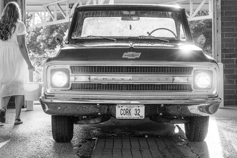 Front view of a classic Chevrolet pickup truck with headlights on in black and white.