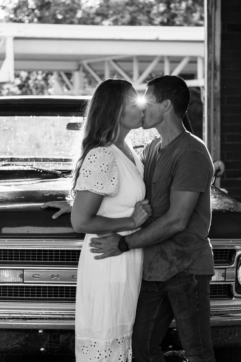Romantic embrace against a vintage Chevrolet truck in black and white photography.